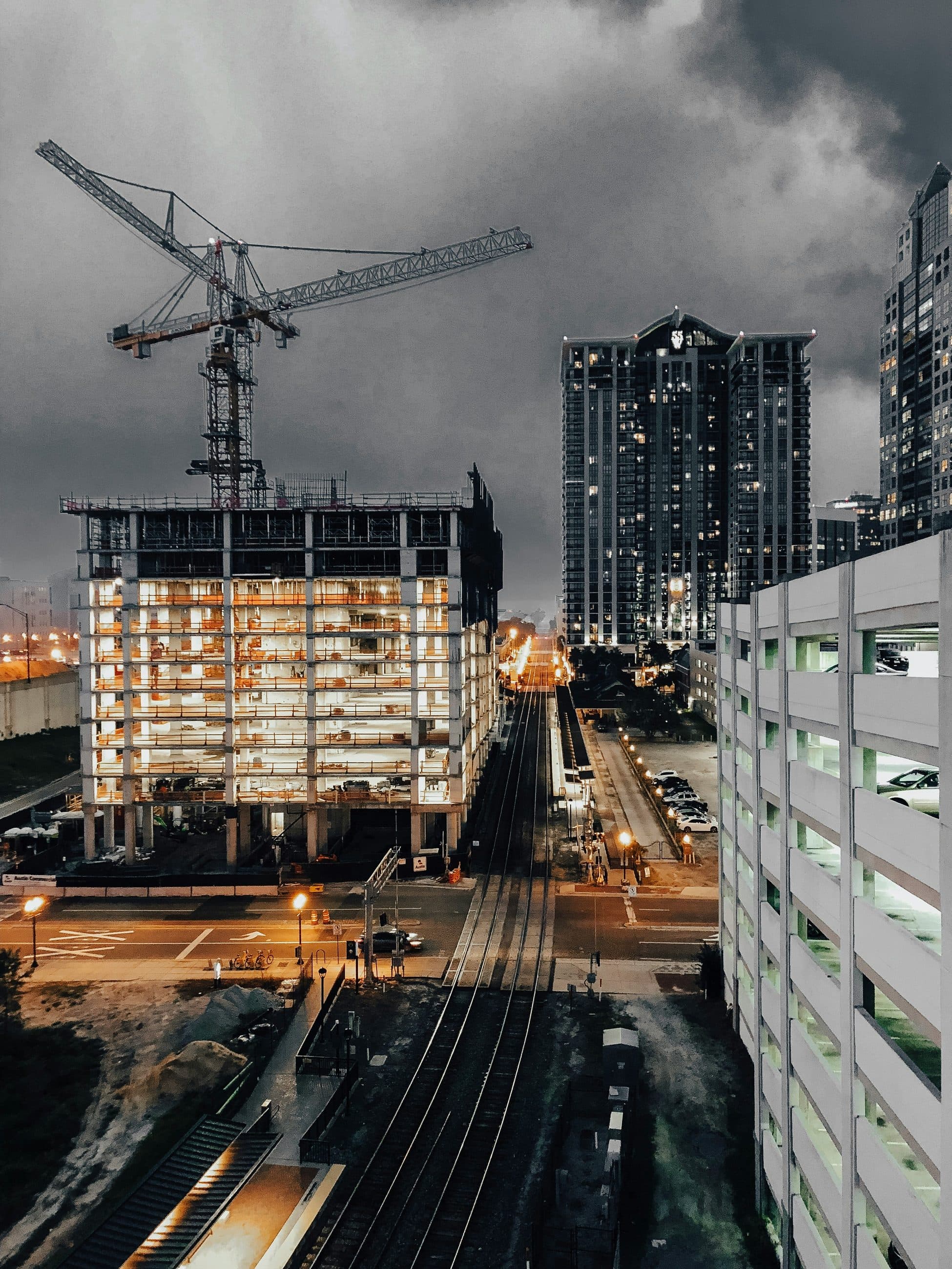 Construction cranes over a city skyline at dusk