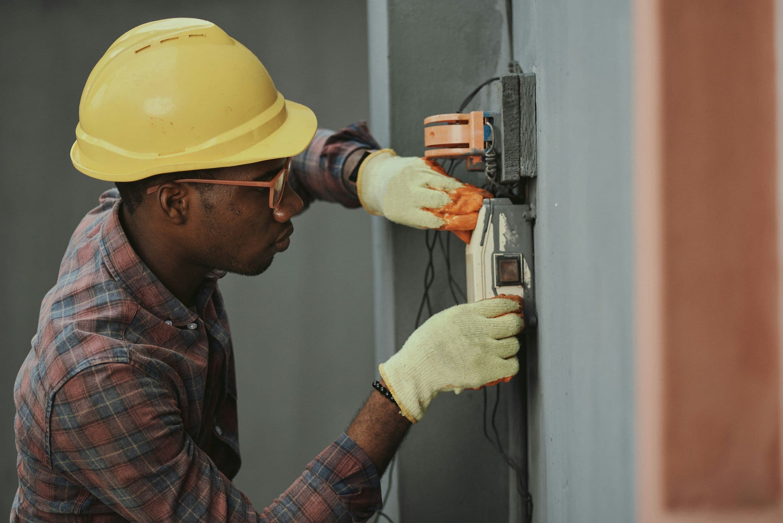 Electrician in protective gear working on a wall-mounted junction box