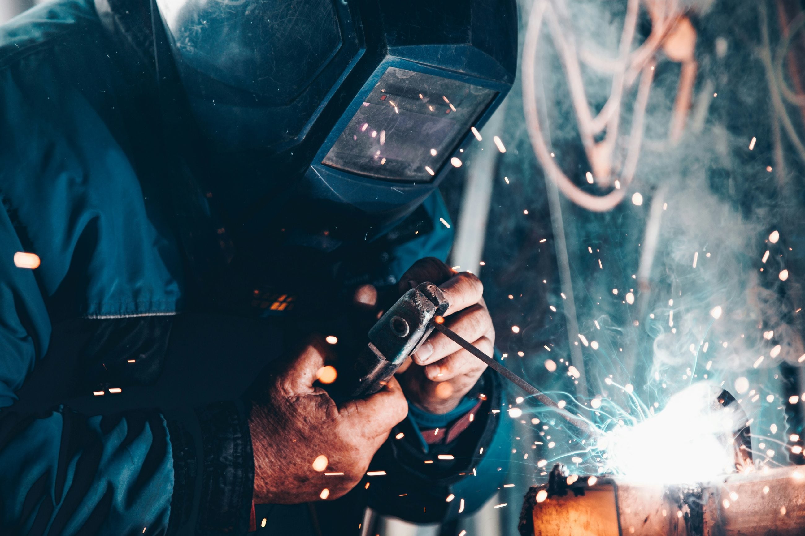 Welder working on a steel joint, sparks lighting the workshop